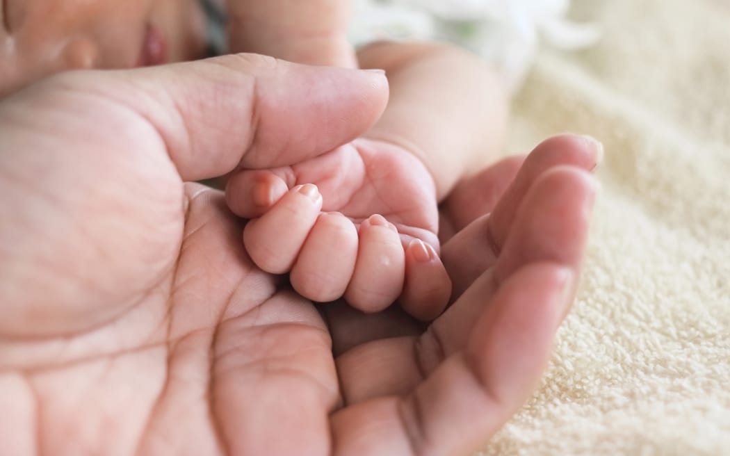 Soft focus of newborn tiny baby hand on parent hands.