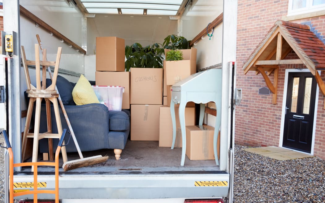 Removal Truck Waiting To Be Unloaded Outside New Home On Moving Day