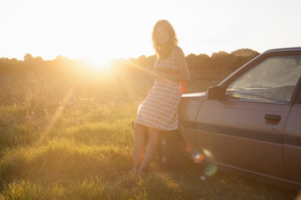 Portrait of mid adult woman leaning against car at sunset (Photo by Axel Bernstorff / Image Source / Image Source via AFP)