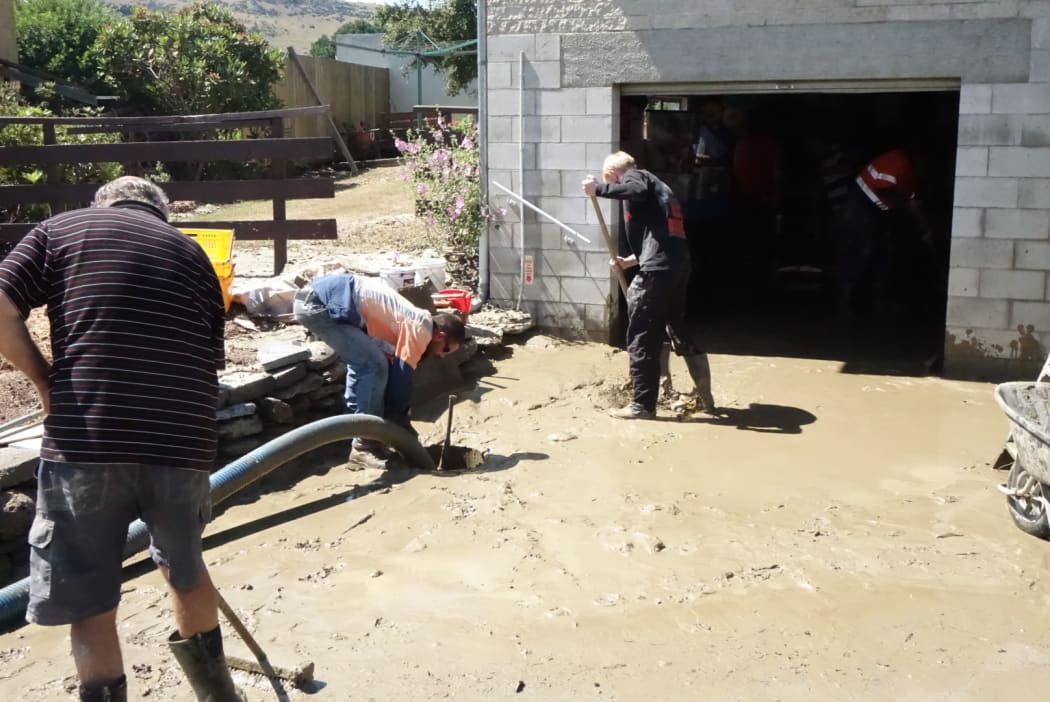 Residents dig out silt from a flooded property in Roxburgh
