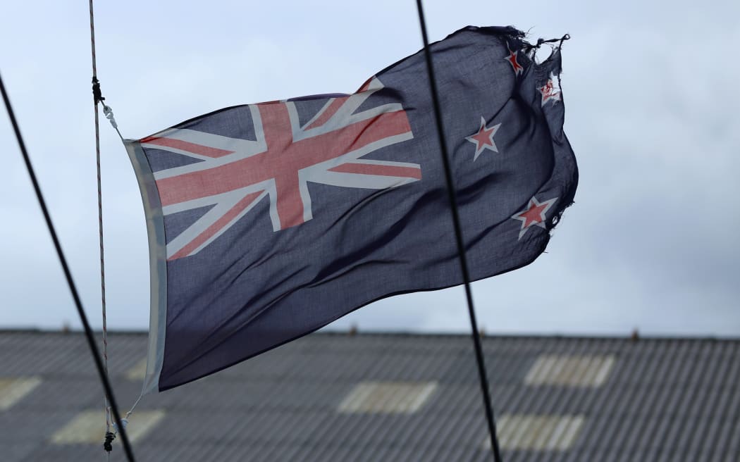 Tattered New Zealand flag flying high on a yacht in Wellington.