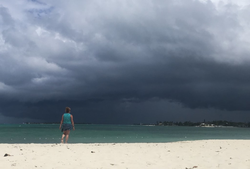 A woman walks on the beach as a storm approaches in Nassau, Bahamas.