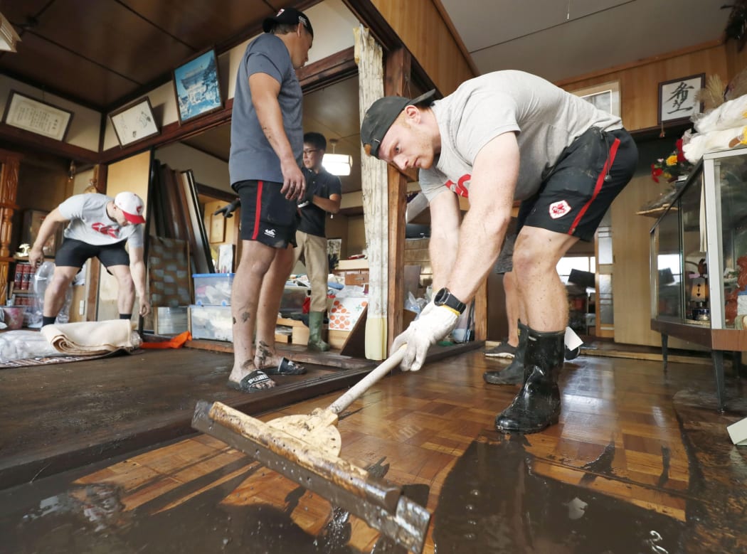 Canada's national rugby union team player Peter Nelson and other teammates help remove mud inside a house at a flooded area, caused by Typhoon Hagibis in Kamaishi.