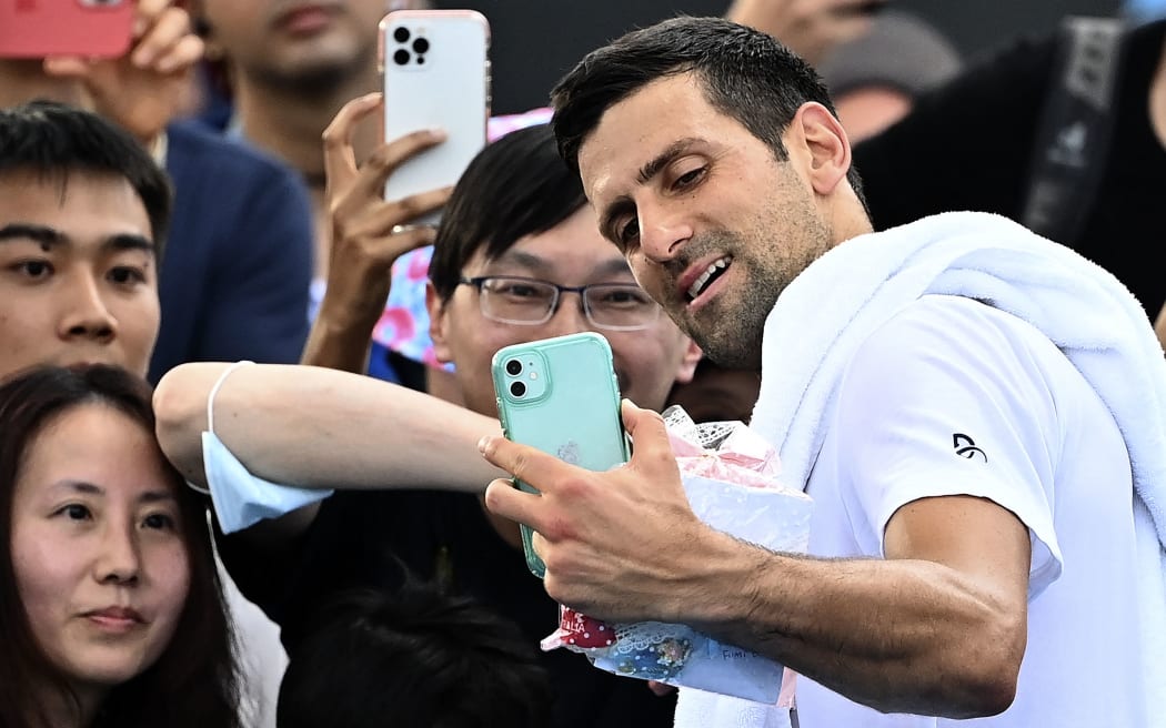 Serbia's Novak Djokovic takes selfies with fans after a practice session on day two of the Australian Open tennis tournament in Melbourne on January 17, 2023. (Photo by MANAN VATSYAYANA / AFP) / -- IMAGE RESTRICTED TO EDITORIAL USE - STRICTLY NO COMMERCIAL USE --