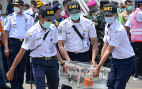 Indonesian officials carry a box contain cockpit voice recorder (CVR or blackbox) on March 31, 2021 after it was recovered during search operations for the Sriwijaya Air Boeing 737-500 passenger jet.