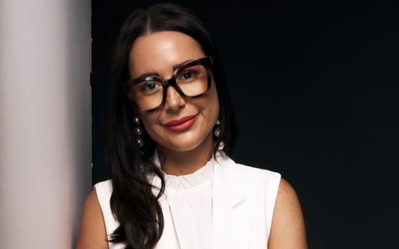 Gabriella Pomare is a dark-haired woman with dark-rimmer glasses and a white sleeveless top.