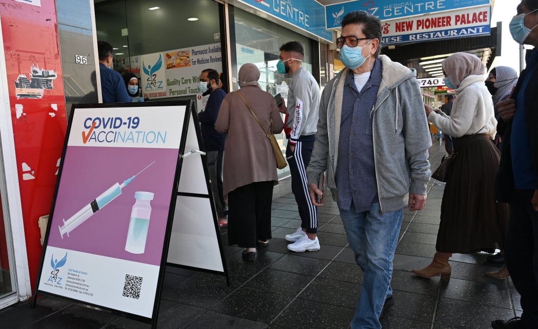 Residents queue up outside a pharmacy for a Covid-19 vaccination in western Sydney on July 30, 2021. (Photo by Saeed KHAN / AFP)