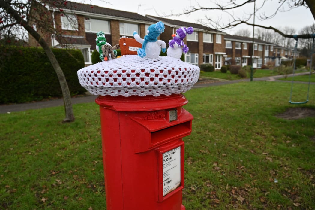A Christmas-themed decoration of knitted snowmen, on the top of a traditional red Royal Mail post box in Shoreham, southern England, on 22 December.