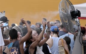 Tourists cool off by a water spraying ventilator before entering the Colosseum monument on July 24, 2023 in Rome during a heatwave.