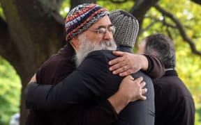 Two men comfort each other in Christchurch on March 17, 2019.