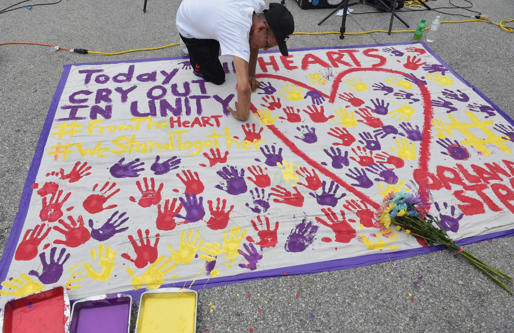 A man places a hand print on a makeshift memorial in a parking lot near the Pulse nightclub in Orlando, Florida on June 12, 2016.
