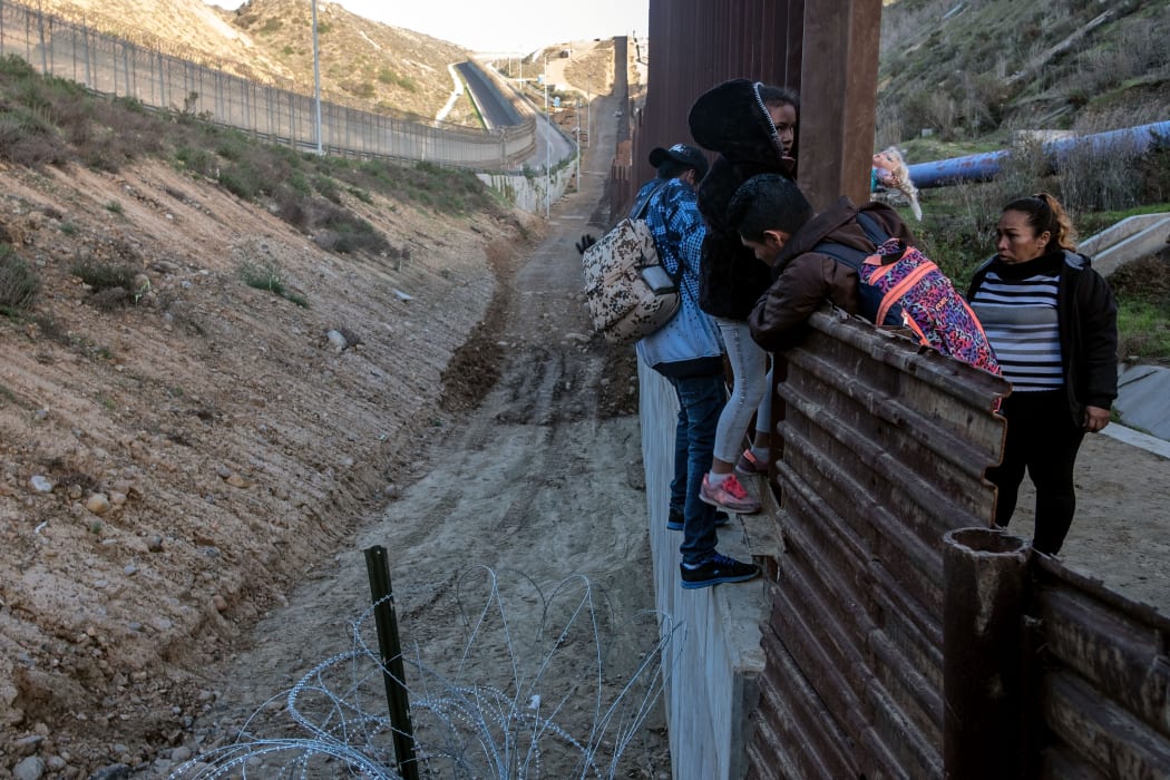 Central American migrants cross the US-Mexico border fence from Tijuana to San Diego County as seen from Tijuana, Baja California State, Mexico, on December 27, 2018.