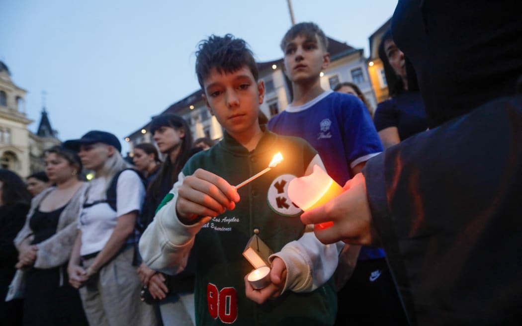 People light candles at a makeshift memorial site after several people died in a school shooting, on June 10, 2025 in Graz, southeastern Austria. Austrian Chancellor Christian Stocker on Tuesday declared three days of national mourning after a school shooting in the southeastern city of Graz reportedly by a former student left ten people dead and several seriously injured. (Photo by Alex HALADA / AFP)