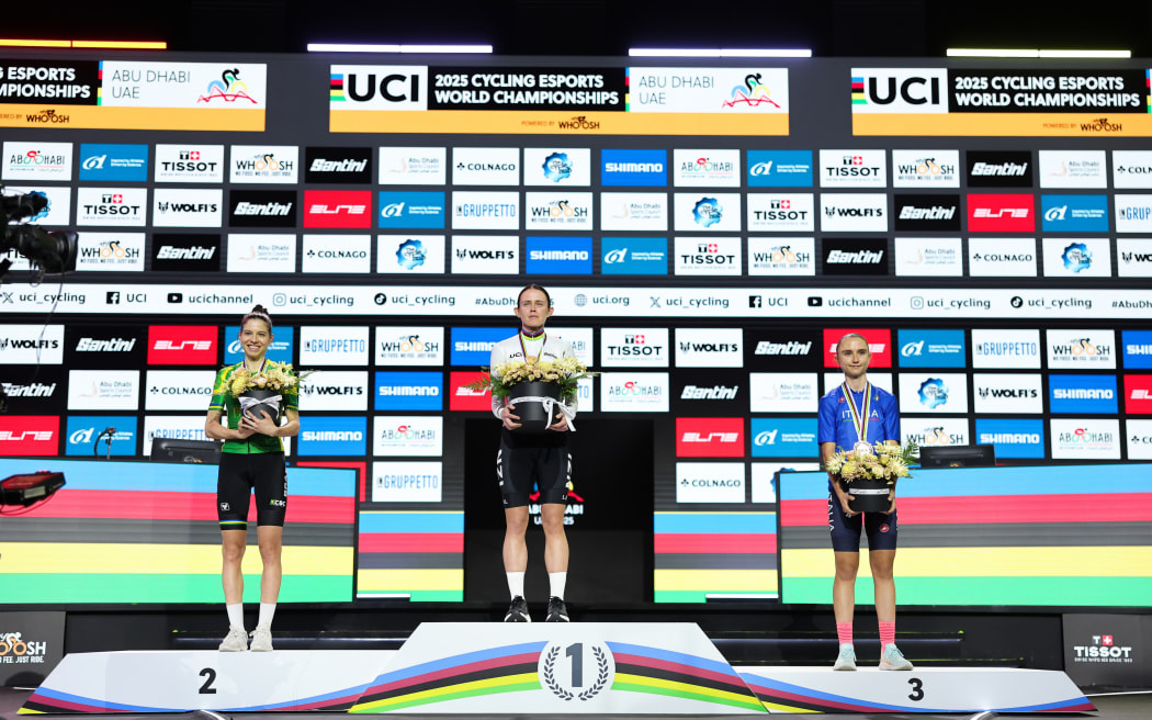 Picture by Alex Whitehead/SWpix.com - 15/11/2025 - Cycling - 2025 UCI Cycling Esports World Championships powered by MyWhoosh - Space42 Arena, Abu Dhabi, UAE - Elite Women Podium - Kate McCarthy (New Zealand) receiving the Gold Medal to become the Esports World Champion, Gabriela Guerra (Brazil) receiving the Silver Medal and Francesca Tommasi (Italy) receiving the Bronze Medal