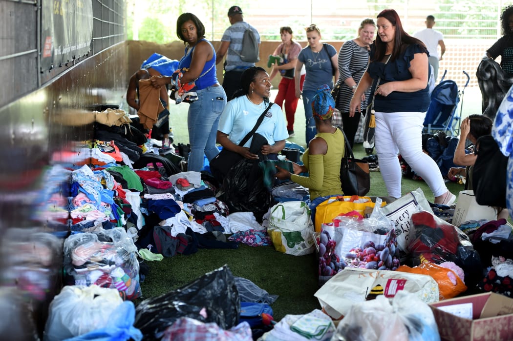 Local residents sort through clothing donated clothes for the evacuees from the burned tower block.