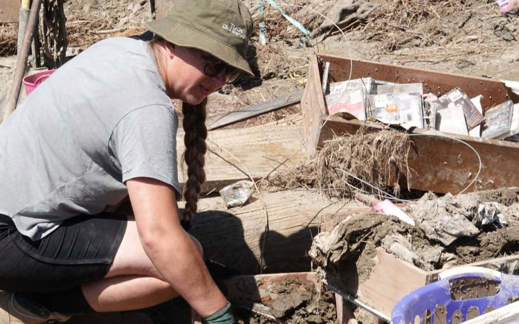 Emma Tuck searches through the silt for belongings.