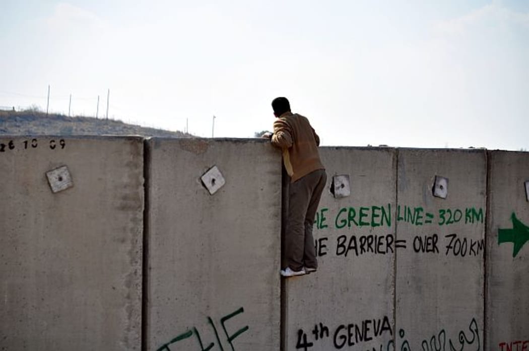Young man man climbs concrete separation wall