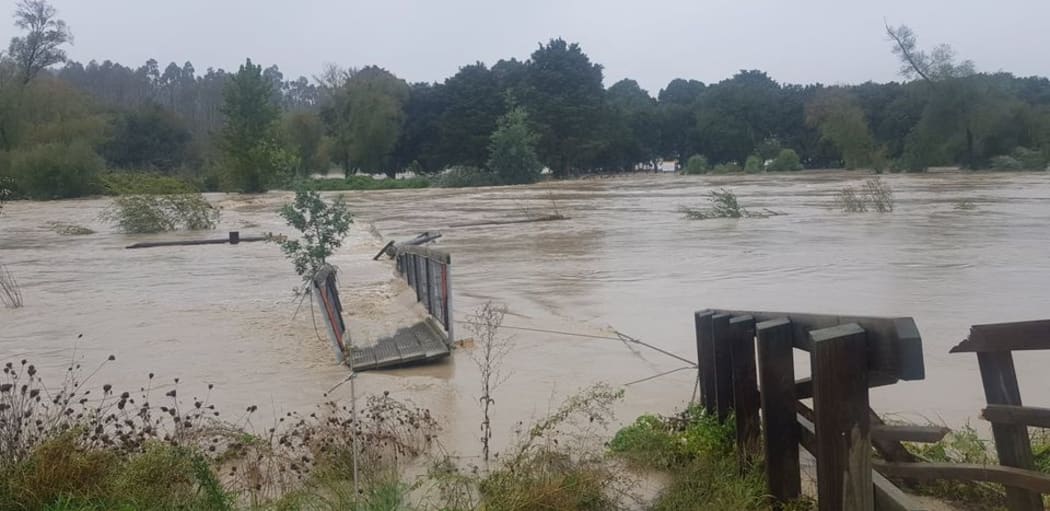 The swing bridge over the Tukituki River, Hawkes Bay, was swept away in the flooded river.