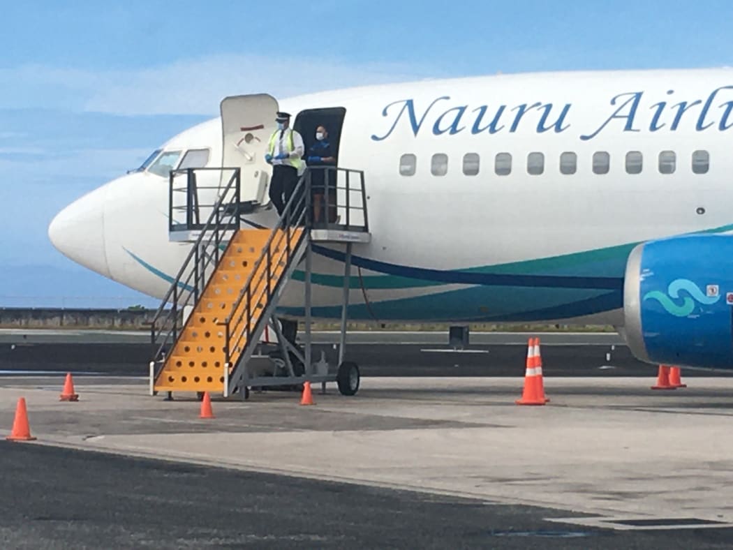 A Nauru Airlines pilot, donned in Covid-19 prevention gear, waits for local officials to collect flight manifest documents. No passengers or crew deplaned from Friday's flight to Majuro, which took about 10 passengers out of Majuro.