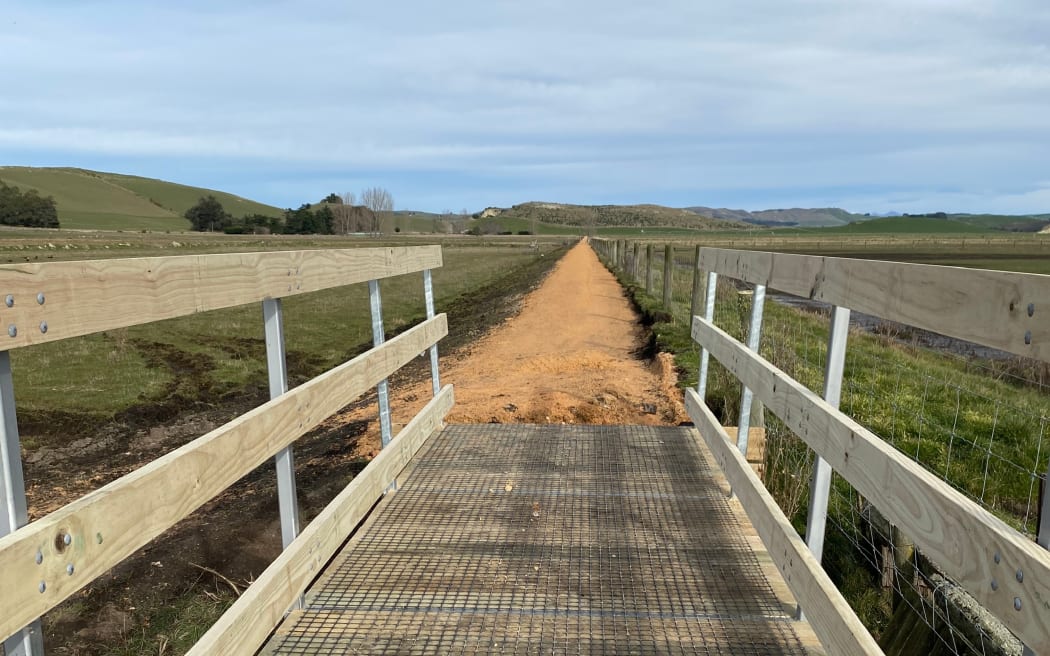 One of the bridges on the Waimate Trail in South Canterbury, taken from the bridge looking towards the newly surfaced path through paddocks with hills in the distance