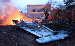 A picture taken on February 3, 2018, shows a Rebel fighter taking a picture of a downed Sukhoi-25 fighter jet in Syria's northwest province of Idlib.