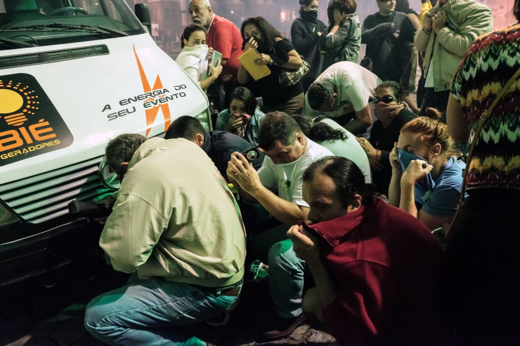 Protesters take cover behind a van from the tear gas fired by the military police during the nationwide strike called by unions opposing austerity reforms in Rio de Janeiro, Brazil, on April 28, 2017.