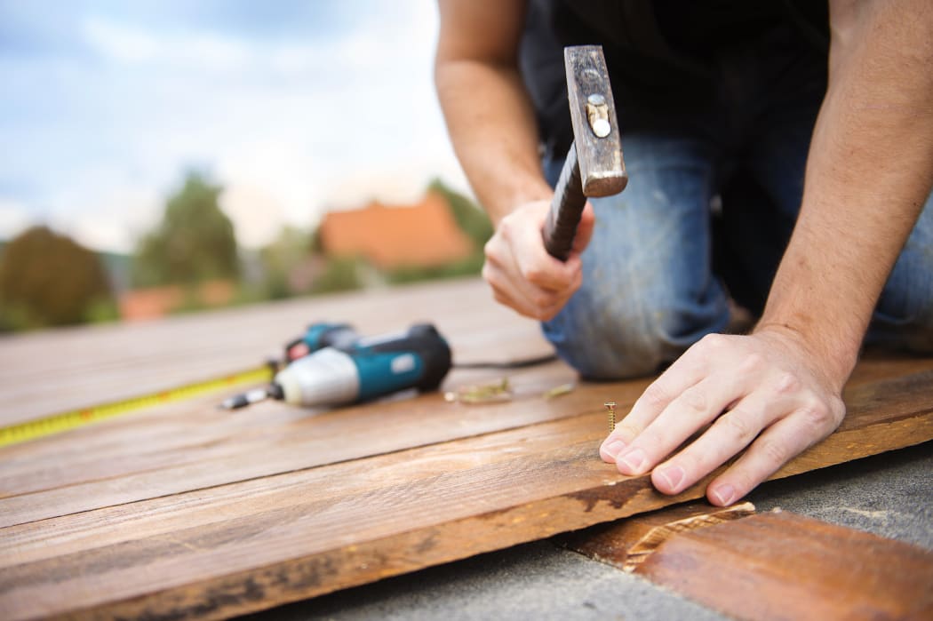 A worker hammers down timber for a house's deck.