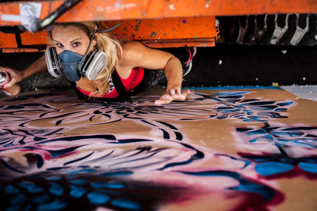Artist Hayley King, aka Flox, working on a mural in Hamilton
