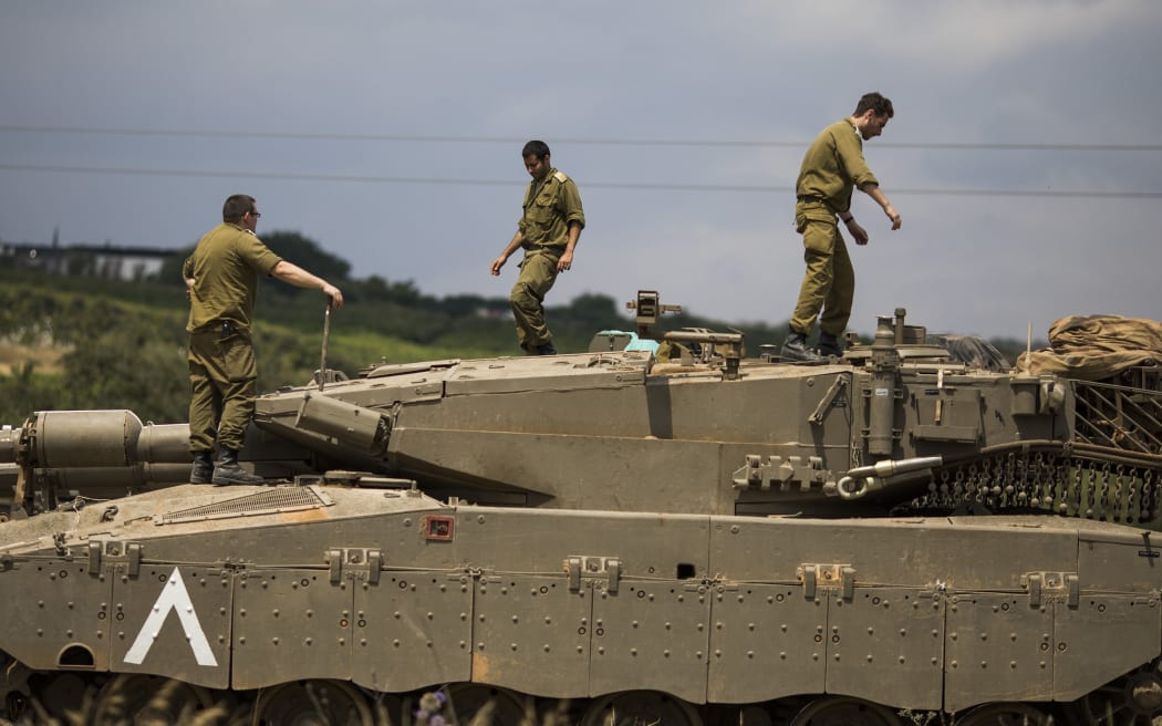 Israeli soldiers on top of a Merkava Mark IV tank that deployed along the border with Syria.