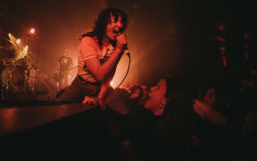 A woman yells into a microphone onstage.