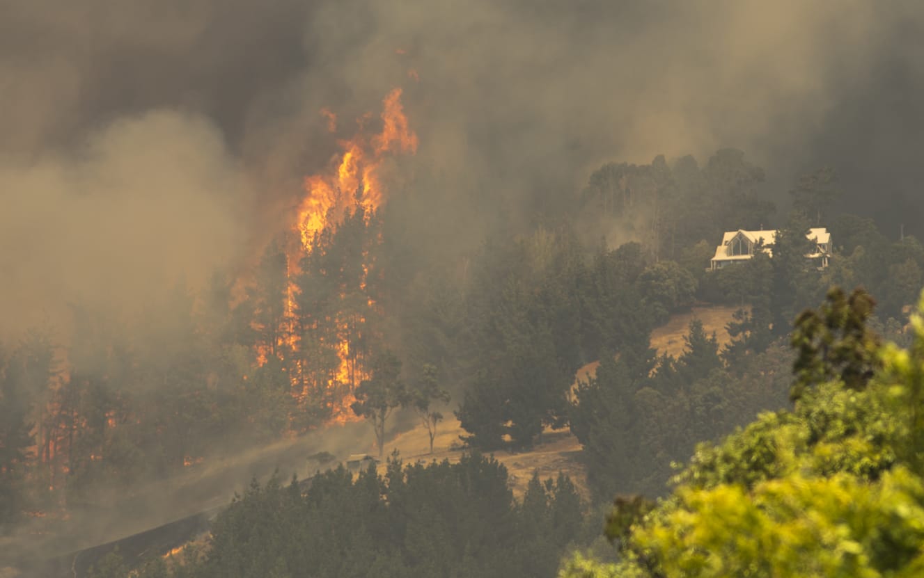 Flames leap close to a house in the Port Hills.