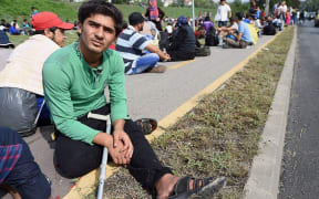 A migrant group of about 500 refugees sits on the pavment next to the main road near Budaors, Hungary, as they head to the Hungarian-Austrian border.