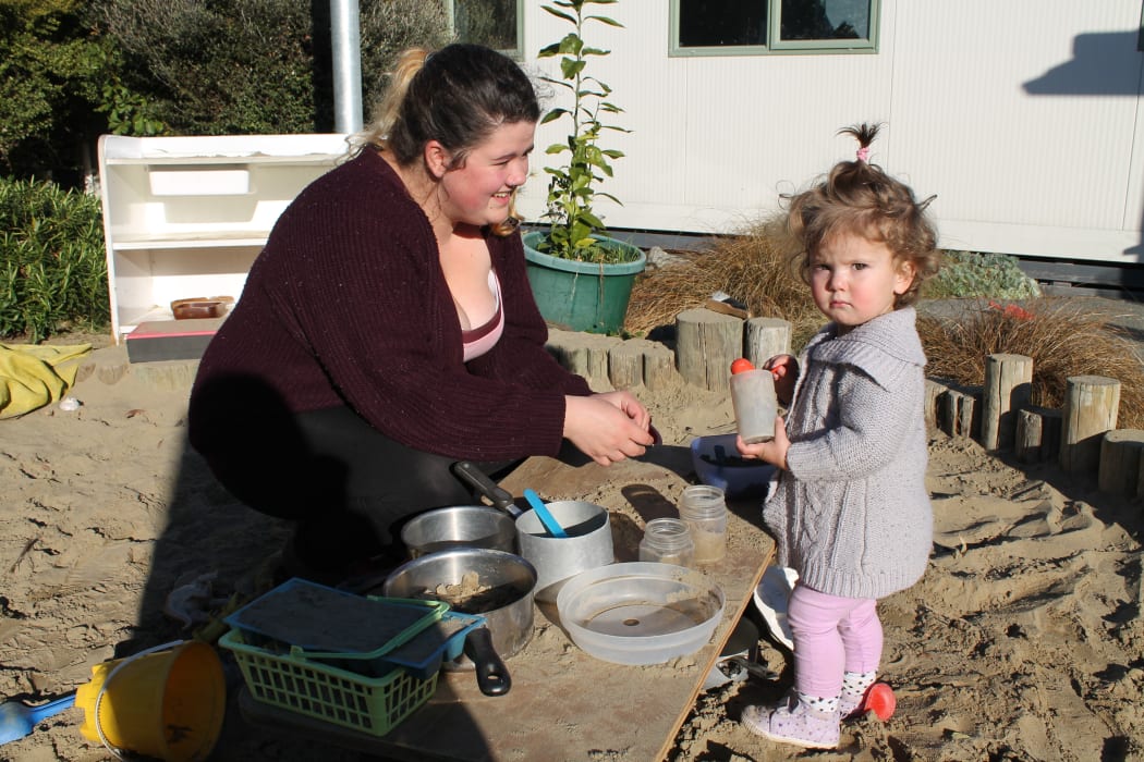 A photo of a young mother, Courtney Watts and her daughter, Sophia in the creche sandpit
