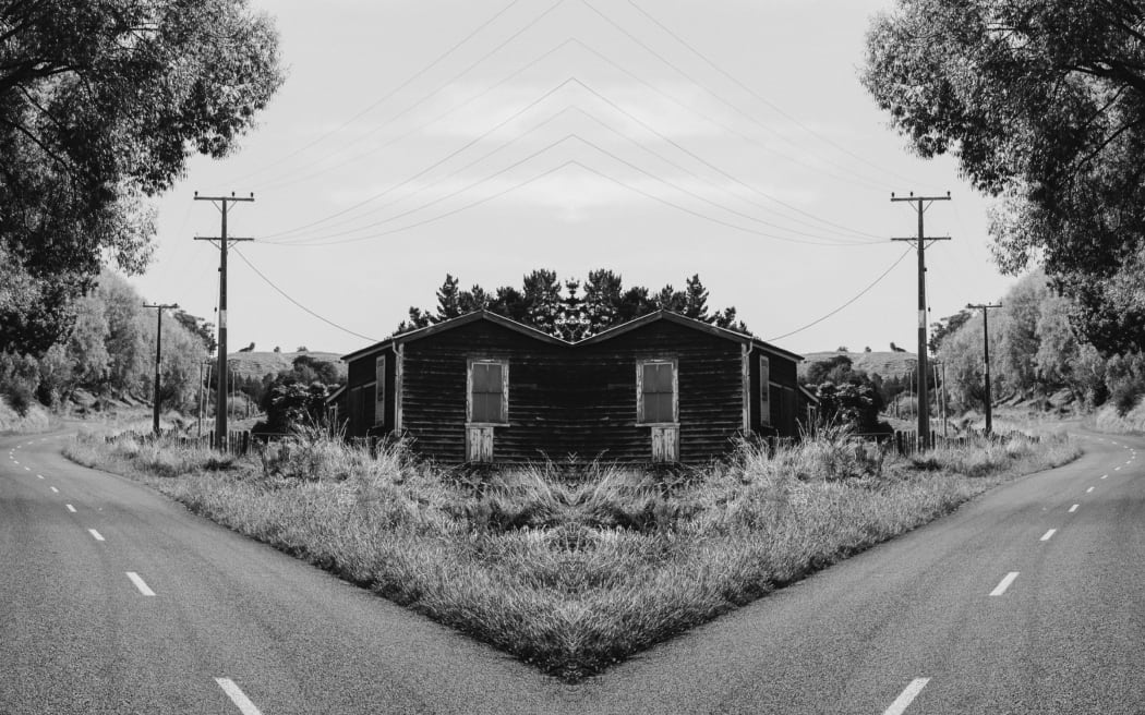 A gothic, black-and-white mirror image of a street in Whanganui featuring a ram-shackle house and powerlines.