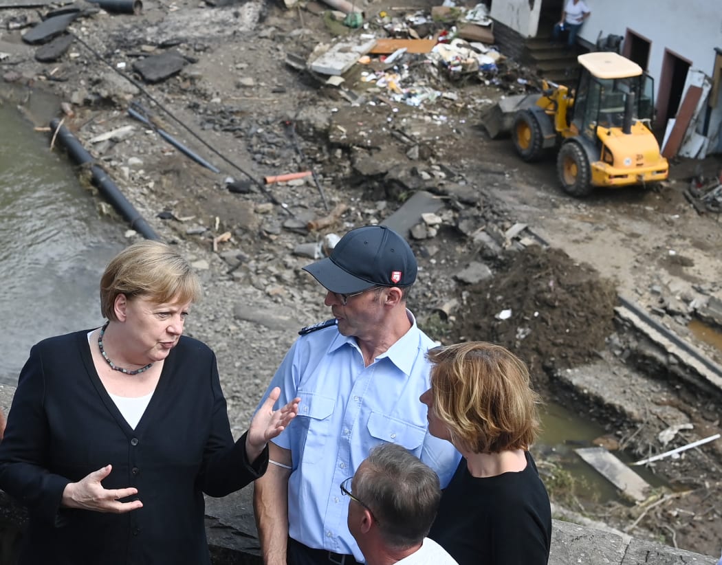 German Chancellor Angela Merkel, left, and Malu Dreyer, right, Prime Minister of Rhineland-Palatinate, stand on a bridge overlooking the flood-ravaged village of Schuld near Bad Neuenahr-Ahrweiler.