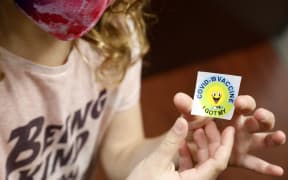 A 7 year-old child holds a sticker she received after getting the Pfizer-BioNTech Covid-19 vaccine at the Child Health Associates office in Novi, Michigan on November 3, 2021.
