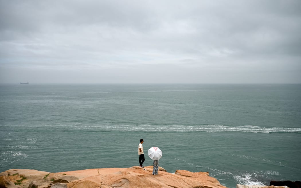A man and a woman look out to the Taiwan strait at a tourist spot called "68 Nautical Miles" on Pingtan island, the closest point in China to Taiwan’s main island, in southeast China’s Fujian province on May 24, 2024. China warned on May 24 that Taiwan's leadership was pushing the self-ruled island into "a perilous situation of war and danger" and that it would go "further" if provoked, as Beijing conducted military drills around the territory. (Photo by Greg Baker / AFP)
