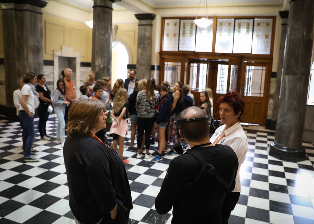 Tour Guides Janet Herbertson (L) and Jennifer Looman chat with Phil Smith on "the Tiles", the first floor foyer of Parliament House. In the background is a school group from Taranaki.