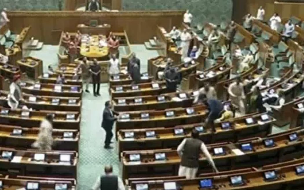 A screen grab as the men jumped over tables and chairs in the Indian parliament chased by security guards and parliamentarians.