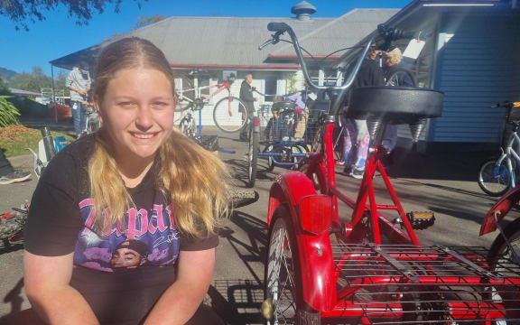 Harlow Bidois with her favourite bike, a red tricycle that she helped to pump the tyres up on. Samantha Gee RNZ.