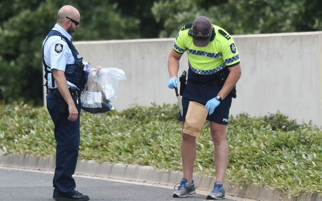 A police officer picks up a knife from a street leading to the ministerial entrance of Parliament House in Canberra.