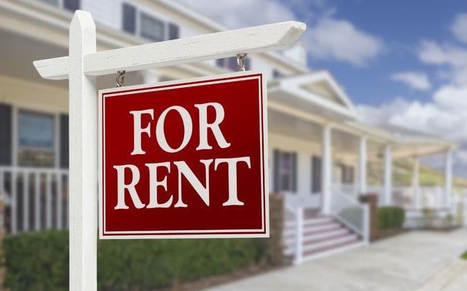For rent sign in front of two-storey houses.