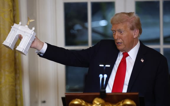 WASHINGTON, DC - OCTOBER 15: U.S. President Donald Trump holds a model of an arch as he delivers remarks during a ballroom fundraising dinner in the East Room of the White House on October 15, 2025 in Washington, DC. Trump hosted organizations and individuals for a fundraising dinner for the new $250 million ballroom addition currently under construction at the White House.   Kevin Dietsch/Getty Images/AFP (Photo by Kevin Dietsch / GETTY IMAGES NORTH AMERICA / Getty Images via AFP)