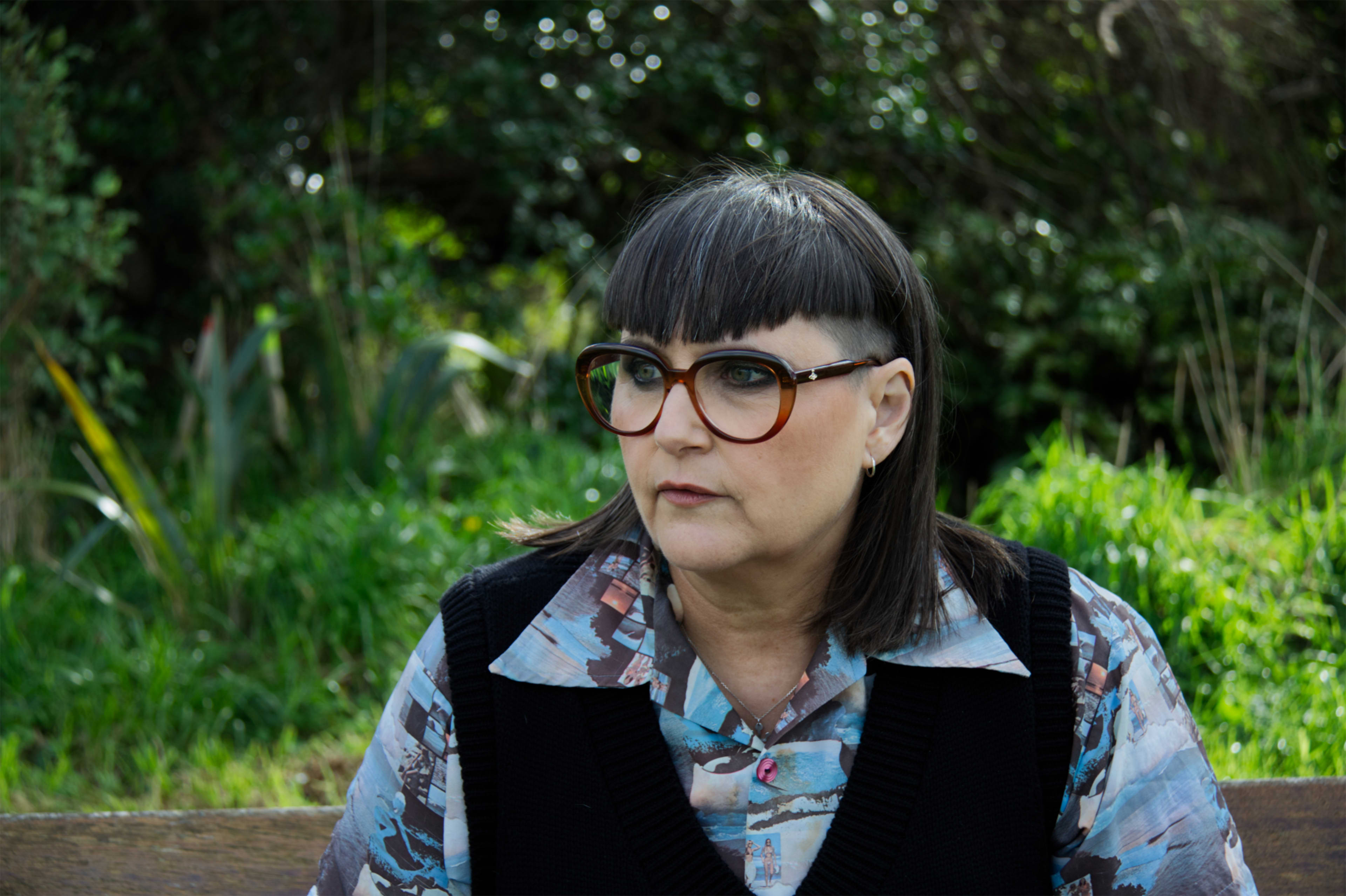 Author Pip Adam looks away from the camera. Pip has black hair in a sharp bob and dark framed glasses.