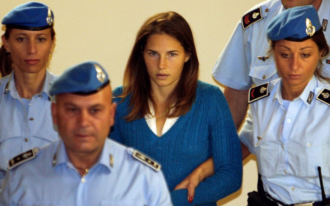 One of the three suspects in the murder of British student Meredith Kercher, Amanda Knox from the US (C), is escorted by police upon her arrival at a court hearing in Perugia on September 26, 2008. Kercher, 22, a student from Leeds University studying in Perugia as part of the Erasmus exchange programme, was found dead in her Perugia apartment on November 1 with her throat cut.  AFP PHOTO/ Federico Zirilli (Photo by Federico Zirilli / AFP)