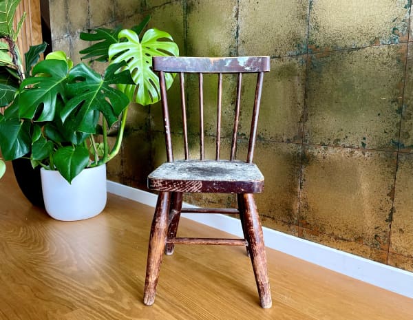 A little brown chair speckled with paint.