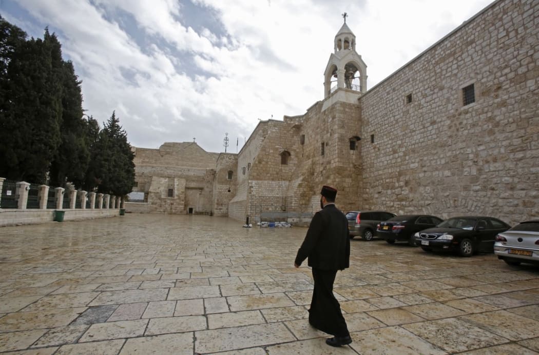 A priest walks past the Church of the Nativity in the West Bank city of Bethlehem, a day after spraying sanitisers as a preventive measure against the coronavirus, on March 6, 2020.