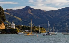 Akaroa lighthouse and harbour with moored yachts, Banks Peninsula, New zealand.