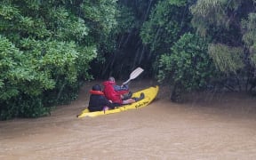 John Welch paddles Jazmyn Welch’s partner Holly to safety after their Kūaotunu home was surround by neck-deep, fast-moving floodwaters.