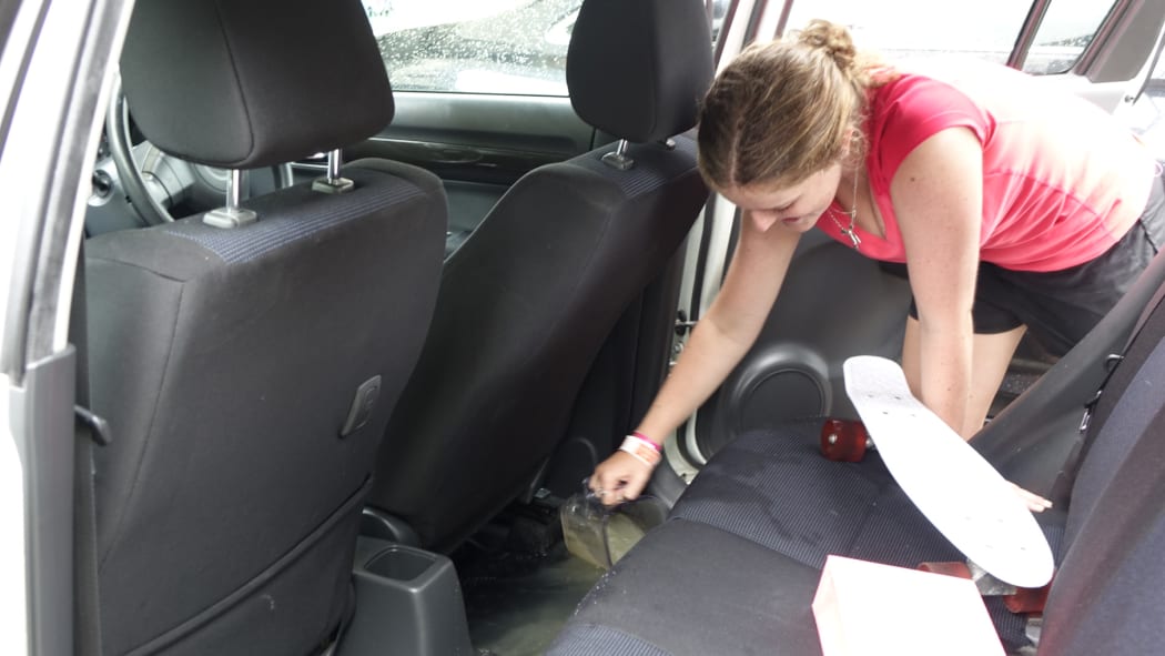 17-year-old Phoebe Nielsen empties her car which was flooded while parked on the road.